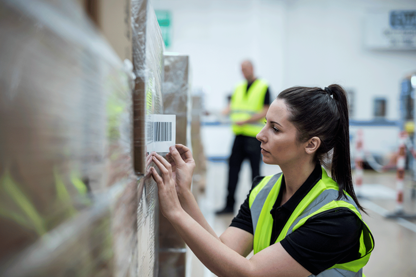 Lady in warehouse marking up pallet for distrubution